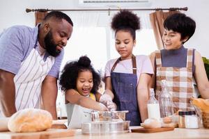 contento africano americano familia disfrutar juntos mientras preparar el harina para haciendo galletas a hogar foto