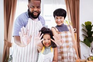 Happy African American family enjoy together while prepare the flour for making cookies at home photo