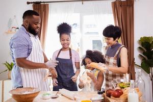 Happy African American family enjoy together while prepare the flour for making cookies at home photo