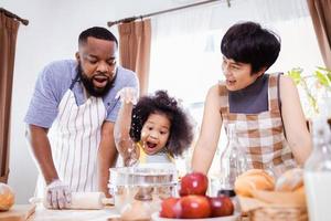 Happy African American family enjoy together while prepare the flour for making cookies at home photo