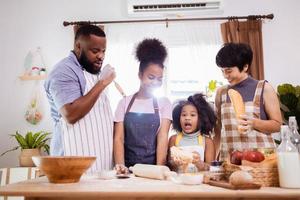 contento africano americano familia disfrutar juntos mientras preparar el harina para haciendo galletas a hogar foto