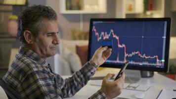 homme investir dans Stock marché jette argent de crédit carte. réfléchi homme investir dans Stock marché et Suivant et en cours d'analyse graphiques de ordinateur. video