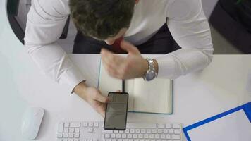 homme d'affaire à la recherche à tiré architectural projets sur le sien téléphone. homme d'affaire séance à le sien bureau en cours d'analyse architectural projet sur le sien téléphone. video