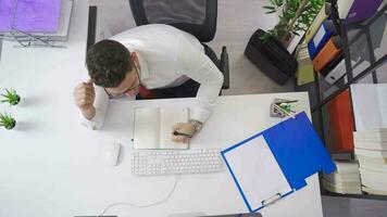 Young architect looking at architectural projects on the phone in his office. The interior designer is browsing the architectural project and making plans on his phone. video