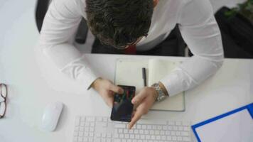 Stock trader businessman analyzing charts on his phone. Cryptocurrency and investment. Businessman trading on the phone at his desk in the office, looking at the stock market charts. video