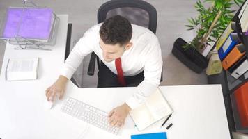 homme d'affaire est en utilisant ordinateur à le sien bureau dans le bureau. homme d'affaire travail dans Bureau en utilisant ordinateur et à la recherche à caméra avec sourire. video