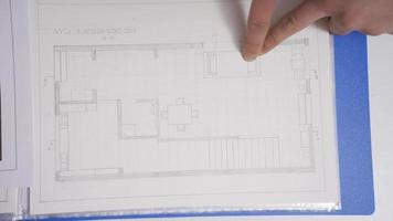 Young male designer sitting at desk and drawing on a house plan, interior design concept. Male interior designer working on a house plan, drawing and using ruler. video