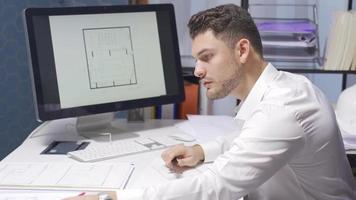 Male Architect are working on a model of a building or shop in the office. The Male Designer develops the architecture and makes new drawings on the project. video