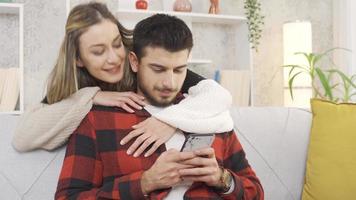 Young happy couple in their modern home. A happy wife wraps her arms around her husband's neck. The newly married young couple is having happy and romantic moments in their home. video