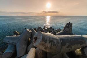 Beautiful sunset seascape. Travel dreams and motivation. Breakwaters tetrapods on shore of pier. Cargo ships on the horizon. photo