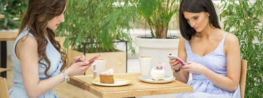 Two women looking their smartphones photo