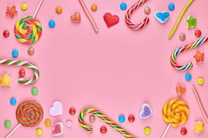 Sweet candy copy space frame with lollipops on pink background photo