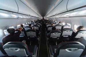 asientos de cabina de avión con pasajeros. clase económica de las nuevas aerolíneas de bajo coste más baratas sin retrasos ni cancelaciones de vuelo. viaje viaje a otro país. foto