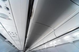 Airplane air conditioning control panel over seats. Stuffy air in aircraft cabin with people. New low-cost airline photo