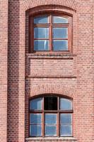 Two arched glass windows set in red brick wall photo