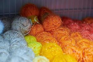 Colored orange and red yarn balls in knitting shop, macro photo