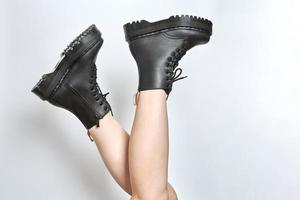 Woman legs in black combat boots on high heel platform with lug soles upside down, white background photo