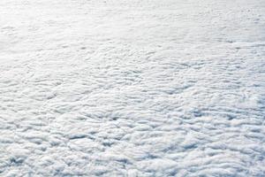 Breathtaking over clouds view from aircraft window, thick white blue clouds looks like soft foam photo