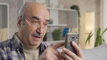 The old man is having trouble using a smart cell phone. The old-fashioned old man is struggling and getting angry with technological gadgets. video