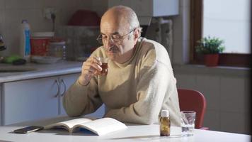 das alt Mann ist beim Zuhause allein lesen ein Buch und Trinken seine Tee. das Mann Wer liest das historisch Buch ist überrascht durch Was er hat gelernt und geht weiter zu lesen das Buch im Staunen. video