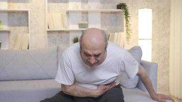 doente velho homem tem estômago dor. pancreático Câncer. a velho homem é sentado em a sofá às casa e tem estômago dor. pâncreas, estômago envenenamento, arrepios. video