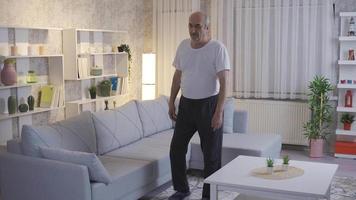 solitaire vieux homme en marchant dans vivant pièce à maison. le vieux homme, qui est inconfortable dans le sien jambes, est en marchant à l'intérieur le maison et vies seule. video