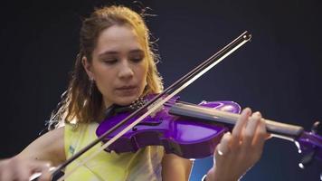 violinista joven mujer jugando el violín. el músico compone un canción o pedazo en un musical instrumento. video