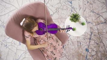 musicista donna seduta su divano a casa e giocando violino. positivo musicista donna giocando violino a casa e godendo se stessa. per riposo il anima. video