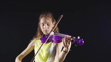 mujer jugando violín en negro antecedentes. enfocado joven violinista mujer jugando violín en negro antecedentes. video