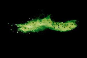 Split debris of  stone exploding with green powder against black background. photo