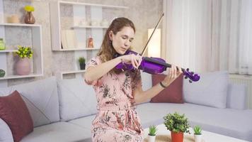 giovane musicista donna giocando sua violino a casa, comporre canzoni, produrre. elegante donna giocando il violino nel il vivente camera a casa riposa sua anima. video