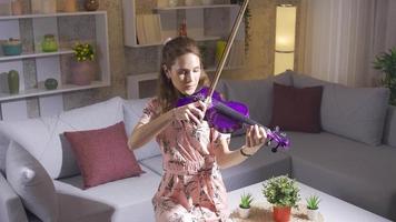 jovem mulher jogando a violino sozinho dentro a vivo quarto às lar. jovem músico mulher composição música tocam dela peça em a violino. video