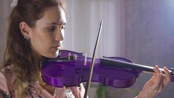 violoniste Jeune femme en jouant violon à maison, fermer. souriant talentueux musicien Jeune femme en jouant la musique sur sa violon seul à maison. video