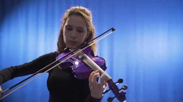 detailopname van jong vrouw musicus spelen viool Aan stadium en haar viool. detailopname van vrouw spelen viool Aan opera stadium of muziek- hal. video