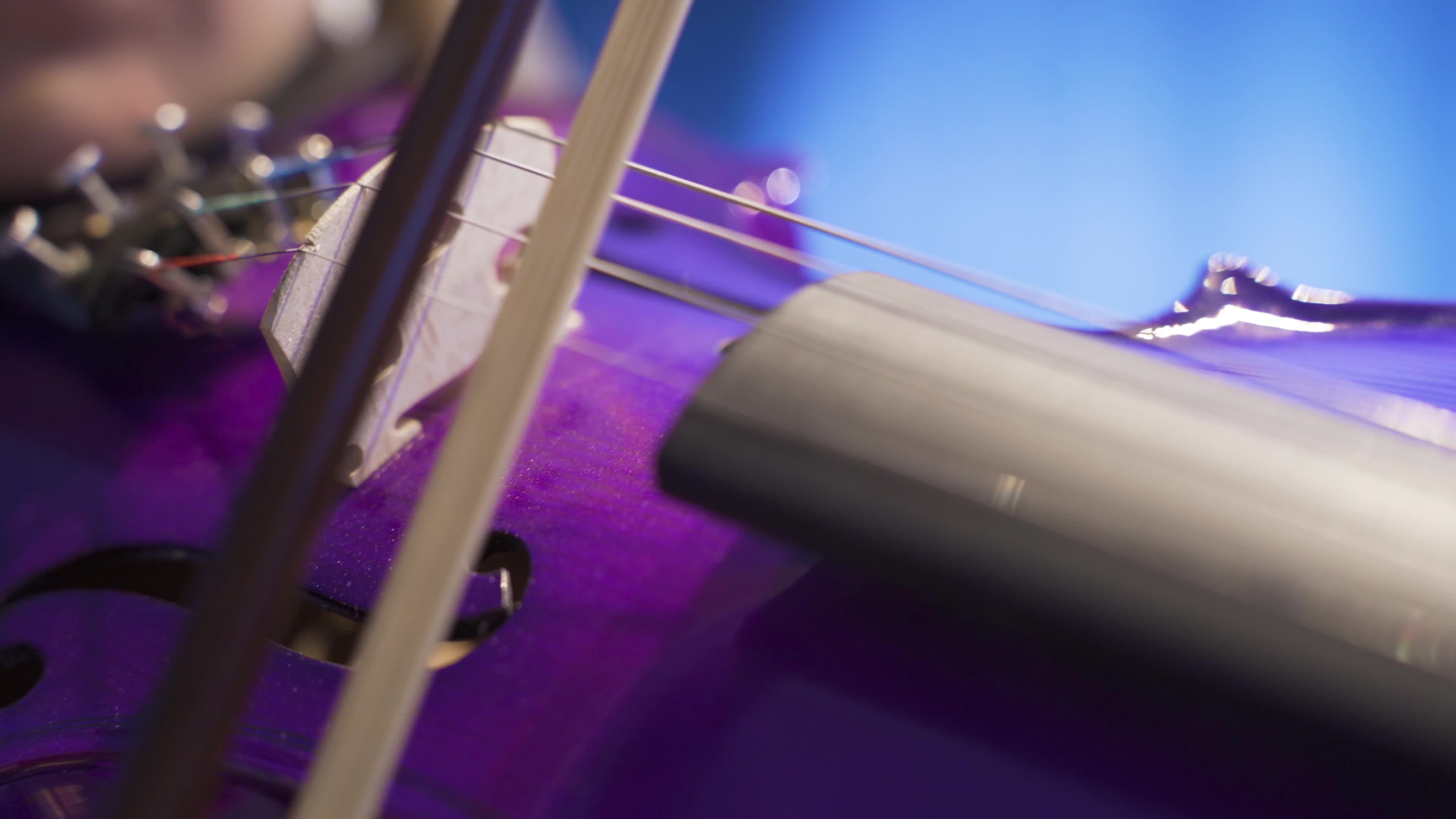 Playing the violin closeup. Musician woman hitting violin strings with