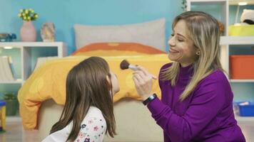 Mom puts makeup on her curious little cute daughter. Funny and cute girl. Cute little girl asks her mother to put make up on her, curious girl. video