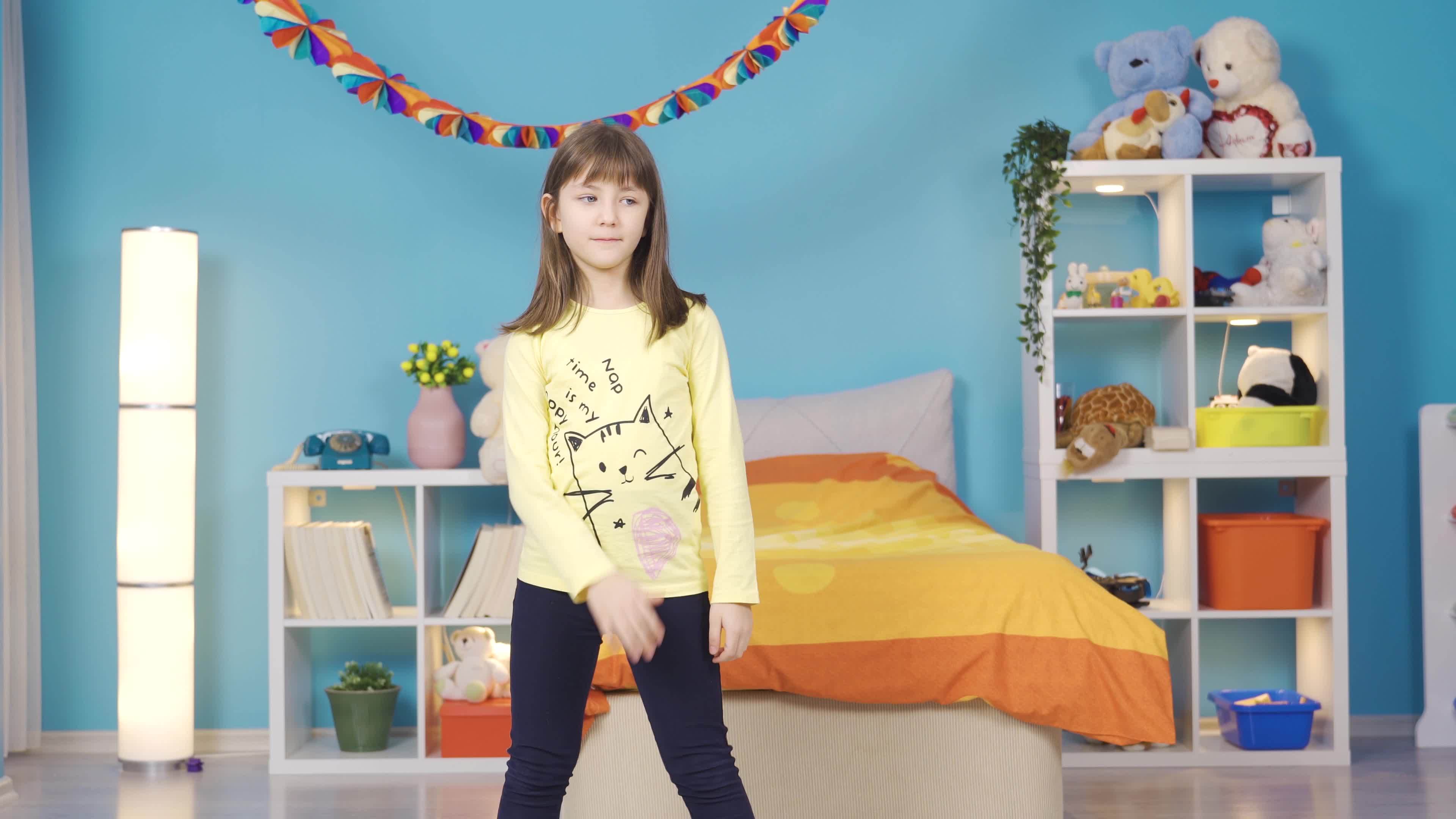 Cute little girl is dancing wildly in her colorful modern room