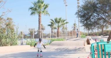 Jugendliche Inliner fahren und Skateboarding im ein Öffentlichkeit Park im das Nachmittag auf ein sonnig Tag. Menschen aktiv Freizeit video