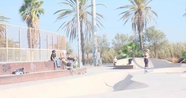adolescentes patinar y patinar en un público parque en el tarde en un soleado día. personas activo ocio video