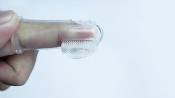 A hand wearing baby tooth brush or infant tooth brush, helping the first teeth clean isolated on white some negative space. photo