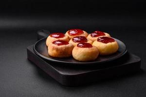 Delicious fresh cottage cheesecakes with raisins and vanilla on a black ceramic plate photo