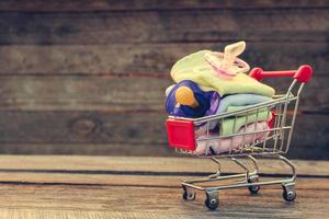 compras carro con ropa y bebé chupetes en el antiguo madera antecedentes. tonificado imagen. foto