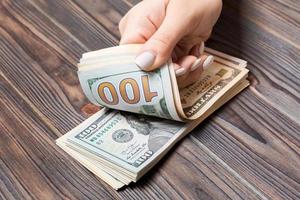 Perspective view of female hands counting money. One hundred dollar banknotes on wooden background. Salary concept. Bribe concept photo