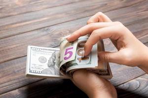 Perspective view of female hands counting money. One hundred and other dollar banknotes on colorful background. Business concept photo