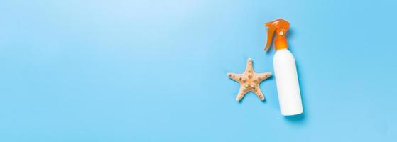 sunscreen cream with starfish and seashells in bottles on blue background, top view photo