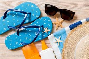 flip flops, straw hat, starfish, sunscreen bottle, body lotion spray on wooden background top view . flat lay summer beach sea accessories background, holiday concept photo