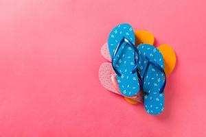 A lot of colored flip flops on pink background. Top view with copy space photo