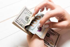 Perspective view of female hands counting money. One hundred and other dollar banknotes on colorful background. Business concept photo