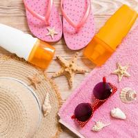 flip flops, straw hat, starfish, sunscreen bottle, body lotion spray on wooden background top view . flat lay summer beach sea accessories background, holiday concept photo