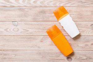 Two Sunscreen bottles on a bright wooden background, top view with copy space photo